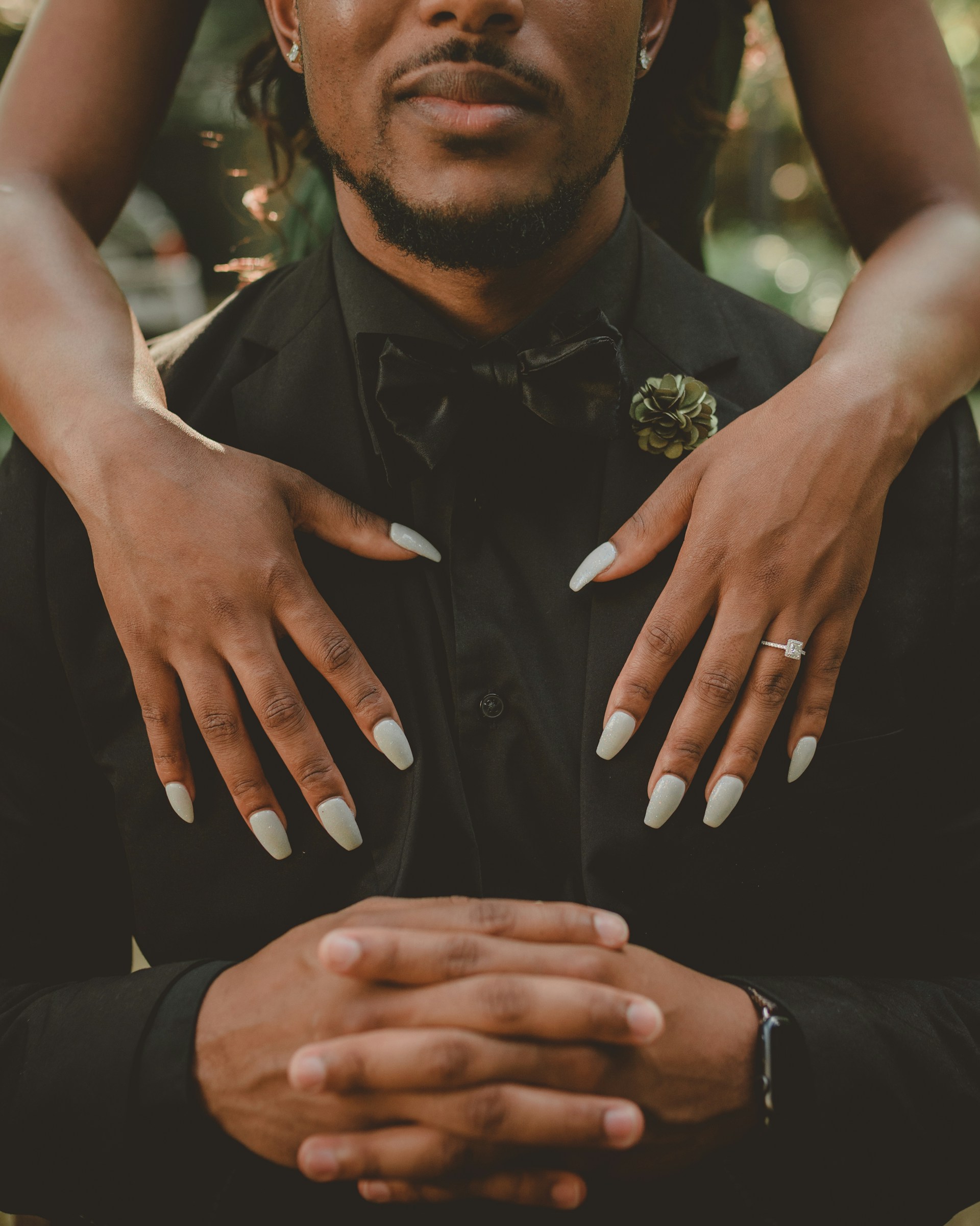 man sitting in chair with woman standing behind him. womans hands on mans chest man sitting in chair, woman standing behind man with hands on mans chest